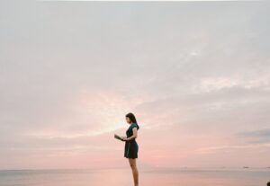 woman wearing black dress standing and reading book